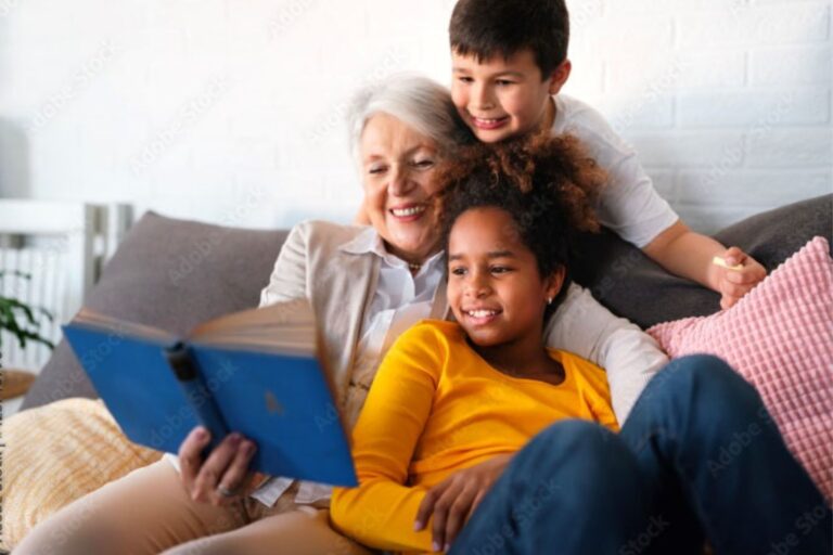 A white woman in her sixties reads a book to two children.